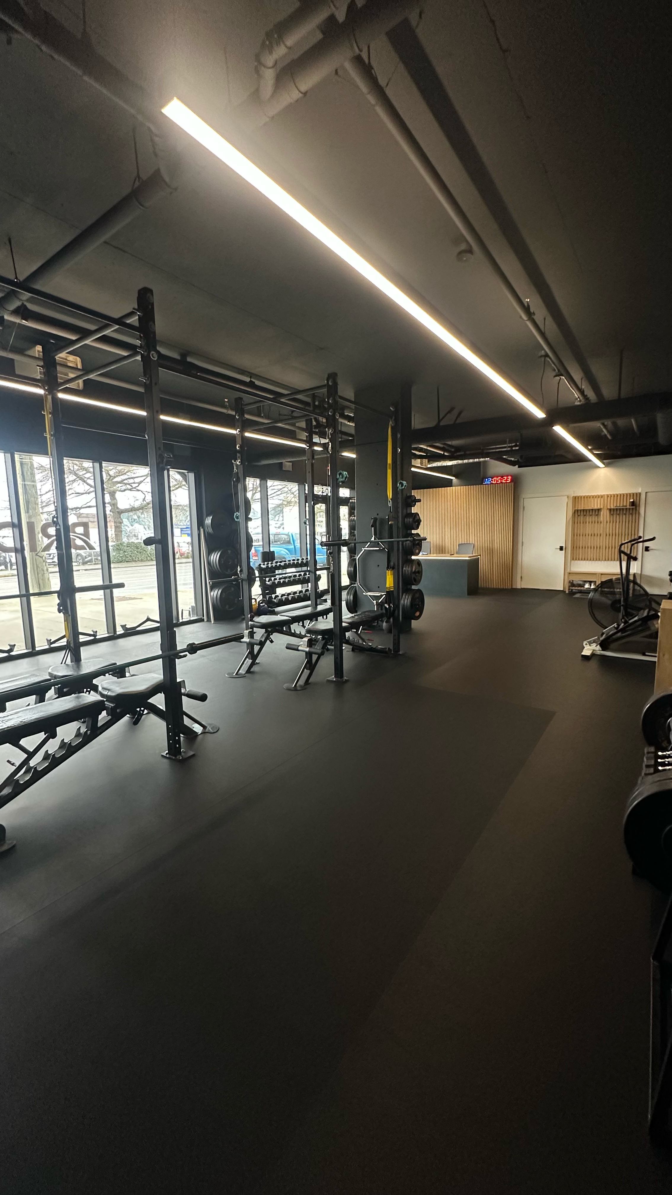 Bridge studio with an open training floor, strength racks, benches, and street-facing windows